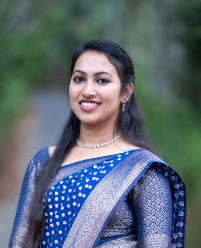 Woman wearing a blue saree with a blurred green background